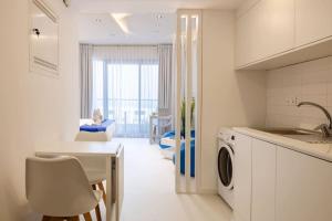 a white kitchen with a table and a laundry room at Marjan Island - Studio Open Sea View in Ras al Khaimah