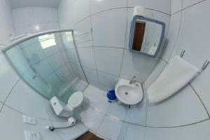 a white bathroom with a toilet and a mirror at CASA CAMINHO do MAR in Pôrto de Pedras