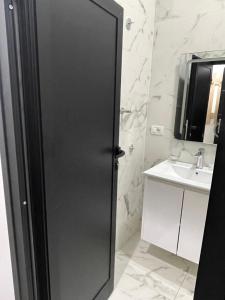 - une porte noire dans la salle de bains pourvue d'un lavabo dans l'établissement Ora Apartament, à Pogradec