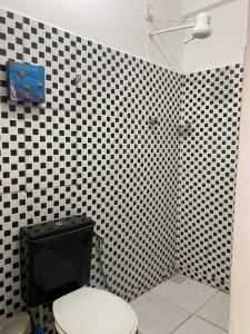a bathroom with a black and white checkered wall at Hostel Aconchego do Arraial in Arraial d'Ajuda