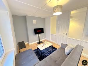 a living room with a couch and a tv at Modern 2 Bed Apartment - FREE Parking - Contractors in Morpeth