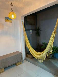 eine gelbe Hängematte, die in einem Zimmer mit einem Bett hängt in der Unterkunft Hostel Aconchego do Arraial in Arraial d'Ajuda
