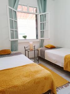 duas camas num quarto com duas janelas em Home & Flower - Private bedrooms Funchal no Funchal