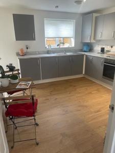 a kitchen with white cabinets and a wooden floor at Walsall New Large House with Garden in Pelsall