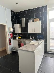 a kitchen with white cabinets and a black tile wall at 3 Luxury En-suite Bedrooms in Cardiff