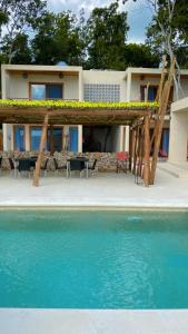 una casa con pérgola junto a una piscina en Azul Maria Bacalar en Bacalar