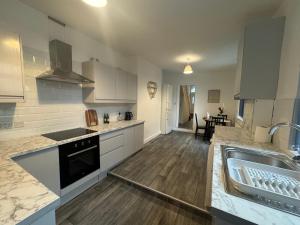 a large kitchen with white cabinets and a sink at Stunning 4 bedroom 8 person 2 bathroom house! in Hull