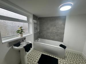 a bathroom with a sink and a bath tub and a window at Stunning 4 bedroom 8 person 2 bathroom house! in Hull