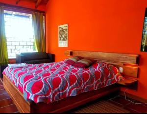 a bedroom with a bed with an orange wall at Arie's Cabin in Pifo