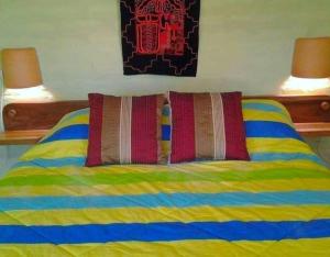 a bed with colorful sheets and two pillows on it at Arie's Cabin in Pifo