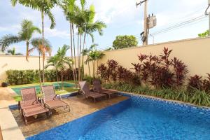 a pool with chairs and palm trees next to a building at PALMAS EXPERIENCE - APARTAMENTO LUXUOSO, vista lago, próximo ao shopping in Palmas