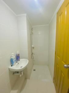 La salle de bains blanche est pourvue d'un lavabo et d'une douche. dans l'établissement 4108 Davao City 2bedroom unit 8 Spatial Maa by Filinvest, à Davao