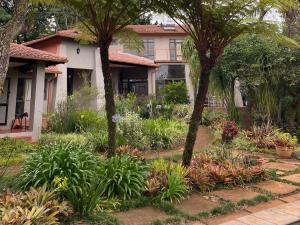 a garden in front of a house with trees and plants at Ambience Inn in White River