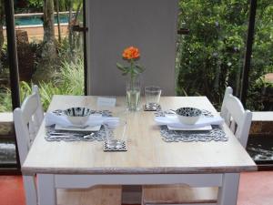 a white table with a vase with an orange flower at Ambience Inn in White River