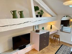 ein Wohnzimmer mit einem TV und einem Schreibtisch mit einem Stuhl in der Unterkunft Charmant cocon sous les toits de Bordeaux in Bordeaux