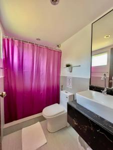 a bathroom with a pink shower curtain and a toilet at Batis ni Juan Leisureland in Dipaculao