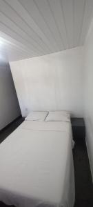 a white bed with two pillows in a room at Pousada Elefantinho in São Pedro da Aldeia