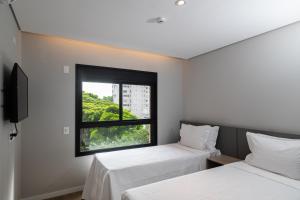 two beds in a room with a window at EZ Moema Hotel in Sao Paulo