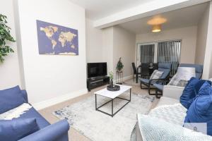 a living room with blue couches and a tv at Modern 4-Bedroom 2-Bathroom with Off Road Parking in Great Sankey by Amazing Spaces Relocations Ltd in Great Sankey