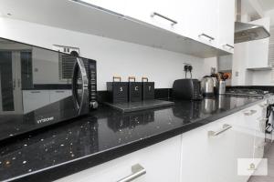 a kitchen with a black counter top with a microwave at Modern 4-Bedroom 2-Bathroom with Off Road Parking in Great Sankey by Amazing Spaces Relocations Ltd in Great Sankey