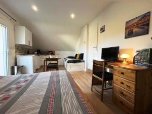 une chambre avec un lit et un bureau avec une télévision dans l'établissement Lomener - La Goelette - studios à 450m de la plage, à Ploemeur