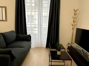 a living room with a couch and a large window at Le Bijou du Martroi in Orléans