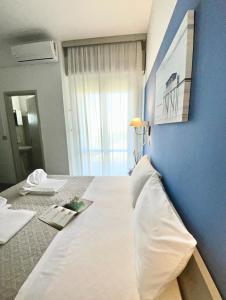 - une chambre avec un grand lit blanc et un mur bleu dans l'établissement Hotel Alfa ALL INCLUSIVE 2024, à Rimini