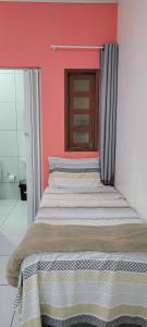 Ce lit se trouve dans une chambre dotée d'un mur rouge. dans l'établissement POUSADA CAMINHO do MAR, à Porto de Pedras