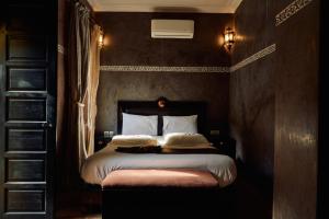 una camera da letto con letto, lenzuola e cuscini bianchi di Riad Dar La Rose a Marrakech