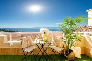 eine Terrasse mit einem Tisch und Stühlen auf dem Balkon in der Unterkunft Sunshine Luxury Vacation House in Puerto de Santiago