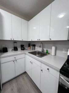 a kitchen with white cabinets and a sink at Prime Location Apt on Calle Ocho in Little Havana in Miami