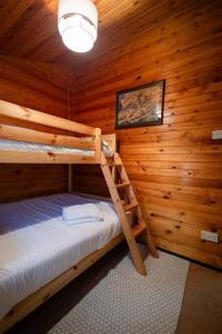 Ffestiniog的住宿－Rural Log Cabin Retreat near Coed y Brenin by Seren Short Stays，小木屋内一间卧室配有两张双层床