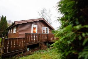 een klein houten huisje met een houten terras bij Rural Log Cabin Retreat near Coed y Brenin by Seren Short Stays in Ffestiniog