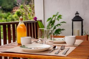 Samburá Paraty في باراتي: طاولة خشبية مع صحون وزجاجة من عصير البرتقال