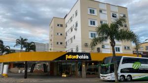 un autobús está estacionado frente a un edificio en Afford Hotéis, en Lages