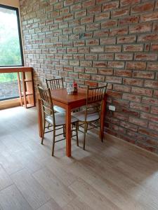 una mesa de madera y sillas en una habitación con una pared de ladrillo en HOSTERÍA QUINTA INÉS MARÍA en Chambo