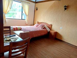 1 dormitorio con cama, mesa y ventana en HOSTERÍA QUINTA INÉS MARÍA, en Chambo