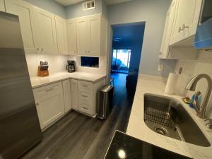 una cocina con armarios blancos y fregadero en Gulf Breeze Condo w Pool Access!, en Gulf Breeze