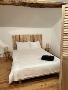 Lesterps的住宿－Gîte à l'ombre des Magnolias，卧室配有白色的床和木制床头板