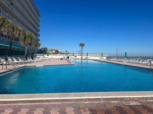 a large swimming pool with chairs and the beach at Ocean Pool King Bed in Daytona Beach