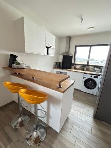 een keuken met witte kasten en een aanrecht met 2 krukken bij Duplex, parking gratuit privé, 5min centre Auxerre in Monéteau