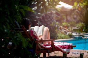 Eine Frau sitzt auf einem Stuhl und liest ein Buch. in der Unterkunft Hotel Boutique Solaz Bella Vista de Colchagua in Santa Cruz