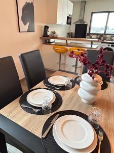 een eettafel met borden en een vaas met bloemen bij Duplex, parking gratuit privé, 5min centre Auxerre in Monéteau