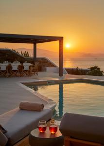 a pool with two glasses of wine and a sunset at Naxea Villas I in Plaka