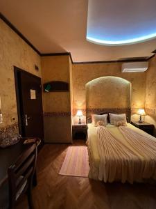 a bedroom with a large bed and a desk with two lamps at Guesthouse Petra in Veliko Tŭrnovo