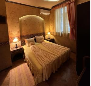 ヴェリコ・タルノヴォにあるゲストハウス ペトラのベッドルーム1室(大型ベッド1台、テーブル2台、ランプ2つ付)