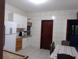 een keuken met een tafel en een witte koelkast bij Casa de praia in Florianópolis