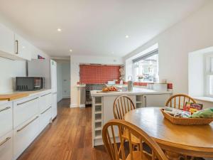 uma cozinha com armários brancos e uma mesa e cadeiras em 4 Bed in Keswick 87567 em Keswick