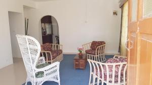 Zimmer mit weißen Stühlen und einem Tisch mit Blumen in der Unterkunft Jetpoint Furnished 2 bedroom in Nadi