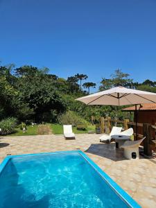 een zwembad met een parasol en twee stoelen en een tafel bij Cabana do Rancho Roque Reis - Wine and Nature in Piedade